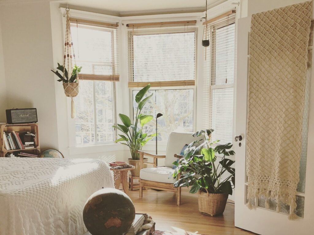観葉植物に囲まれた、木枠の白い椅子のある部屋